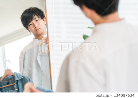 鏡を見ながら服をコーディネートする若いアジア人男性 134087634