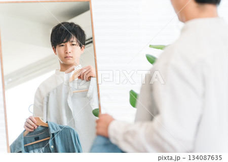 鏡を見ながら服をコーディネートする若いアジア人男性 134087635