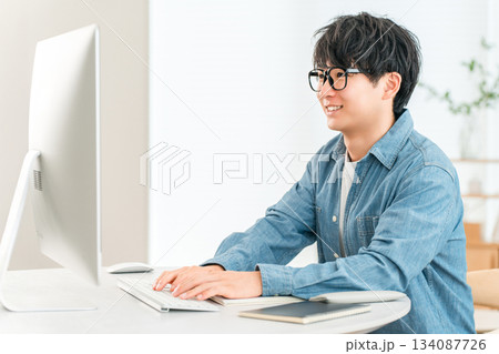 家でパソコンを使ってテレワーク,オンラインセミナー,副業,動画編集をする男性 134087726