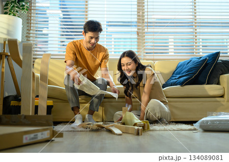 Happy couple reading introduction assembly a new furniture at home Happy couple reading introduction assembly a new furniture at home 134089081