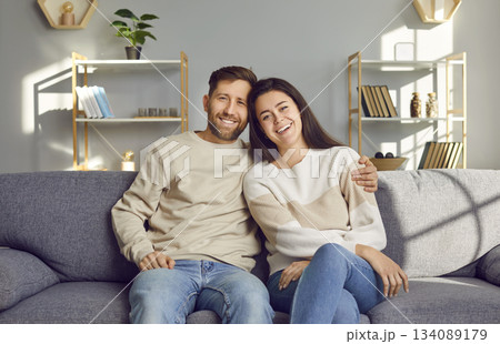 Portrait of a cheerful, smiling young married couple sitting on the sofa at home Portrait of a cheerful, smiling young married couple sitting on the sofa at home 134089179