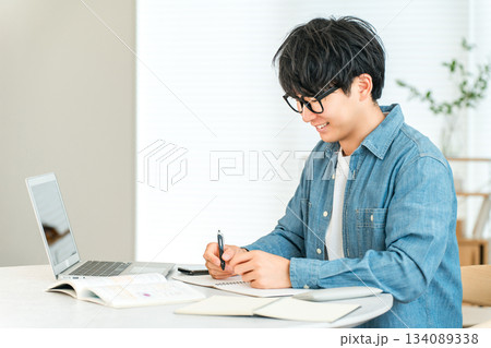 家で勉強する真面目な若いアジア人男性（大学生,卒論,レポート,論文） 134089338