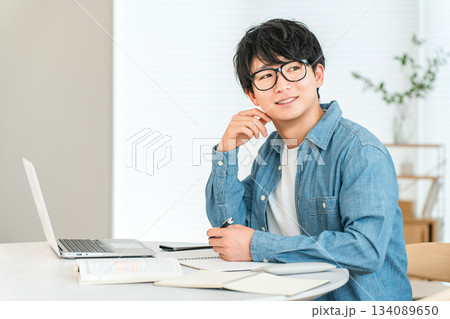 家でスキルアップのために勉強する真面目な若いアジア人男性（自己投資,マネジメント,自宅学習） 134089650