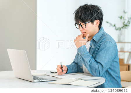 家でスキルアップのために勉強する真面目な若いアジア人男性（自己投資,マネジメント,自宅学習） 134089651