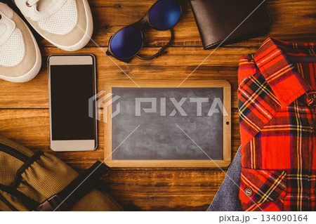 Laying flat on wooden table, showing chalkboard, phone, sneakers, plaid shirt and backpack Laying flat on wooden table, showing chalkboard, phone, sneakers, plaid shirt and backpack 134090164