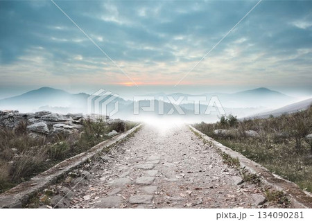 Stony path leading to misty mountain range 134090281