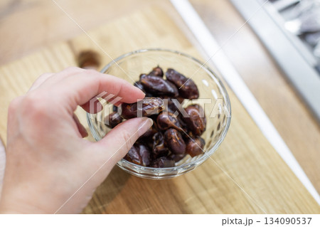Hand picking dried date fruit from glass bowl 134090537
