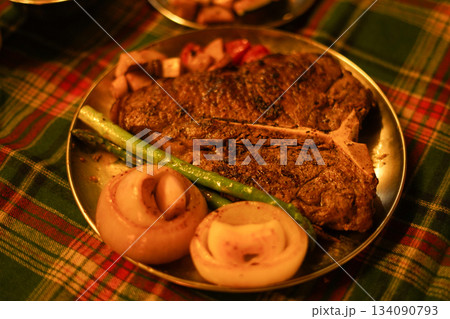Large TBone Steak and Vegetables on a Christmas Themed Plaid Tablecloth 134090793