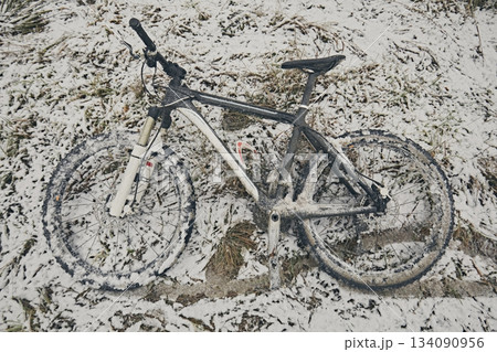 Bicycle in snow and mud in winter against the background of grass 134090956