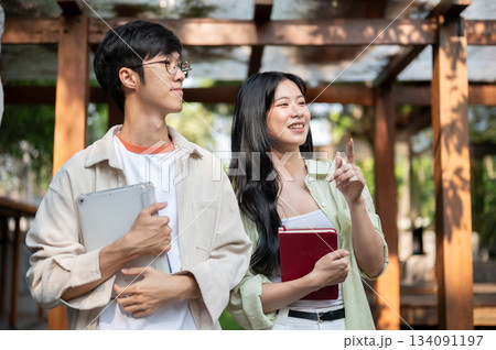 Asian friends or a couple of man and woman are walking and looking around in garden wooden corridor. Asian friends or a couple of man and woman are walking and looking around in garden wooden corridor. 134091197