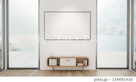 Blank frame over a table between two glass doors of a wooden floor room with snowy scenery outside. Blank frame over a table between two glass doors of a wooden floor room with snowy scenery outside. 134091438