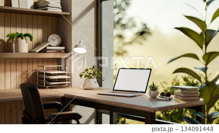 Blank screen laptop on a wooden table and armchair in a glass wall room with nature view outside. Blank screen laptop on a wooden table and armchair in a glass wall room with nature view outside. 134091448
