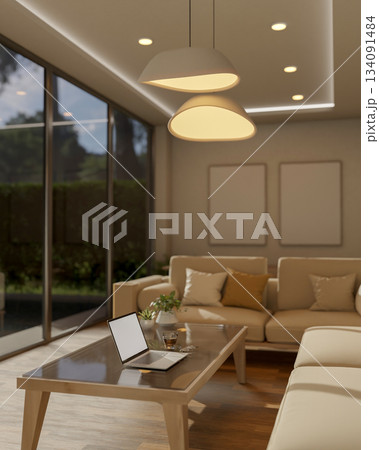 Laptop and coffee on glass top wooden table next to white sofa under warm lamp light in living room. 134091484