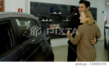Sales manager showing a new car to a female client in the showroom 134091578