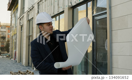 Engineer-architect holding plans on a construction site 134091652
