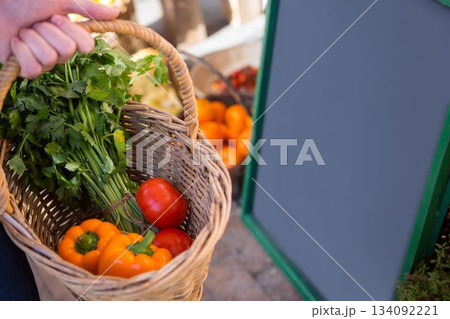 Hand holding a basket full of vegetables in a market 134092221