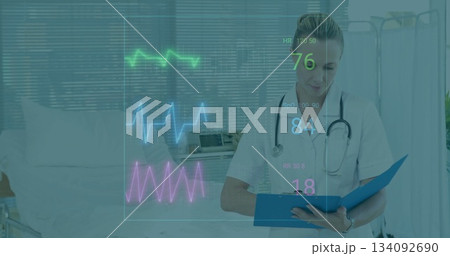 Holding clipboard nurse wearing scrubs and stethoscope reviewing vital waveforms in patient room Holding clipboard nurse wearing scrubs and stethoscope reviewing vital waveforms in patient room 134092690
