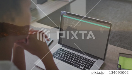 Leaning woman viewing laptop terminal in office, with smartphone and green mesh pouch, copy space Leaning woman viewing laptop terminal in office, with smartphone and green mesh pouch, copy space 134093002