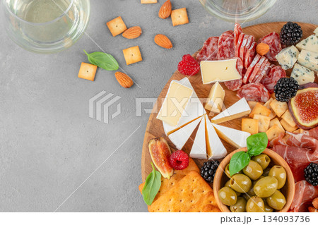 Top view of gourmet charcuterie and cheese board with prosciutto, salami, brie, olives, crackers and berries on gray background with copy space 134093736