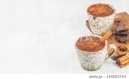 Two cups of hot chocolate with cinnamon and chocolate on white background with copy space, top view Two cups of hot chocolate with cinnamon and chocolate on white background with copy space, top view 134093743