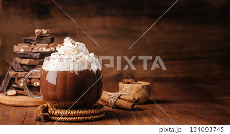 Hot chocolate with whipped cream, cinnamon and chocolate pieces on rustic wooden background with copy space 134093745