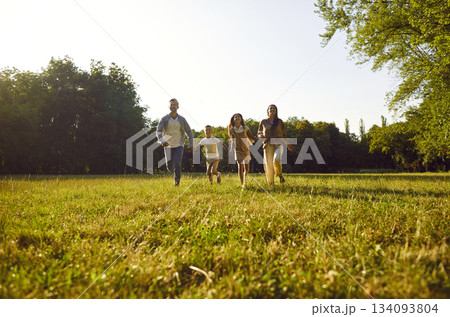 Happy family with two kids running on green grass and having fun in summer park at sunset. Happy family with two kids running on green grass and having fun in summer park at sunset. 134093804