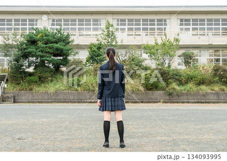 学校の校舎の前に立つ制服姿の中学生・高校生・小学生の後ろ姿 134093995