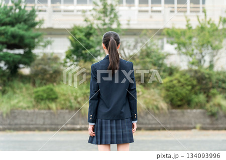 学校の校舎の前に立つ制服姿の中学生・高校生・小学生の後ろ姿 134093996