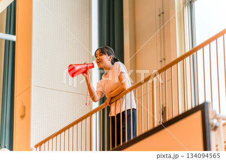 体育館でメガホンを持って応援する体操着姿の女子生徒（エール,声援,頑張れ） 134094565