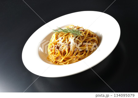 粉チーズとローズマリーの乗ったスパゲッティミートソースを黒背景で撮影 134095079