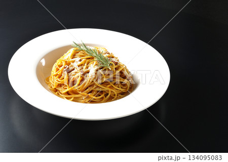 粉チーズとローズマリーの乗ったスパゲッティミートソースを黒背景で撮影 134095083