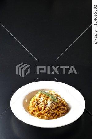 粉チーズとローズマリーの乗ったスパゲッティミートソースを黒背景で撮影 134095092