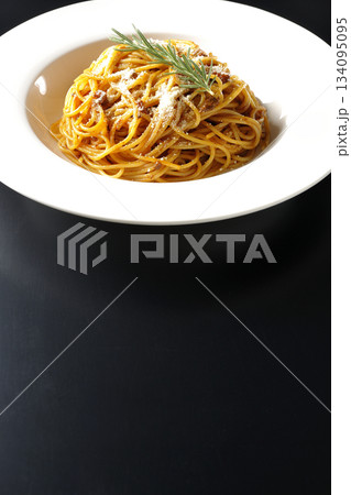 粉チーズとローズマリーの乗ったスパゲッティミートソースを黒背景で撮影 粉チーズとローズマリーの乗ったスパゲッティミートソースを黒背景で撮影 134095095