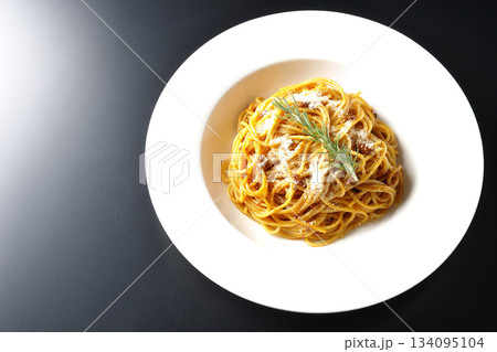 粉チーズとローズマリーの乗ったスパゲッティミートソースを黒背景で撮影 134095104