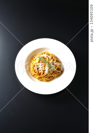 粉チーズとローズマリーの乗ったスパゲッティミートソースを黒背景で撮影 134095109
