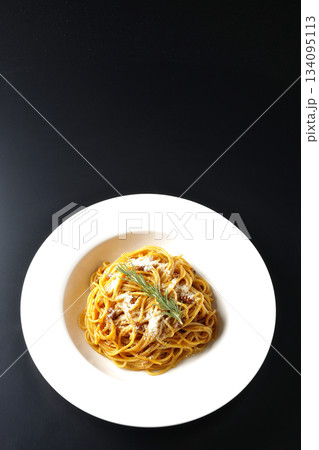 粉チーズとローズマリーの乗ったスパゲッティミートソースを黒背景で撮影 134095113
