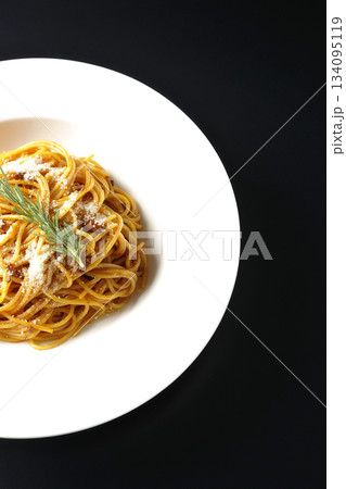 粉チーズとローズマリーの乗ったスパゲッティミートソースを黒背景で撮影 134095119