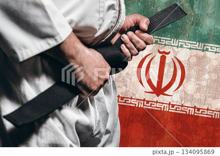 Midsection of martial artist tying belt against Iranian flag 134095869