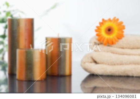 Candles with orange Gerbera daisy on towel 134096081