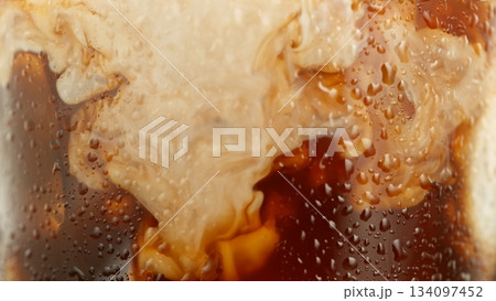 Macro Shot of Pouring Milk into Ice Coffee, Close-up Macro Shot of Pouring Milk into Ice Coffee, Close-up 134097452