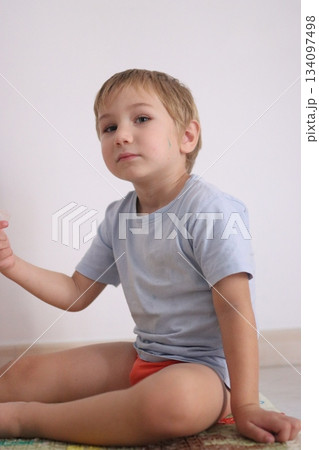 Curious young boy sitting on the floor inside room 134097498