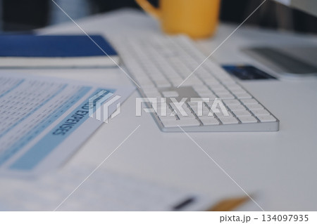 Wooden work desk with laptop and documents, books, modern interior of cozy cabinet, table for businessman or student at home, comfortable workspace, workplace with computer in apartment 134097935