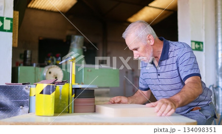 Senior carpenter sanding wood in woodworking workshop Senior carpenter sanding wood in woodworking workshop 134098351