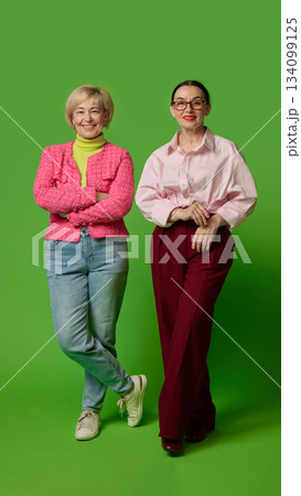 Confident senior women posing together on green backdrop 134099125