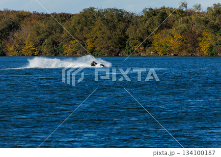 大きな川で波しぶきを上げる水上バイク 134100187