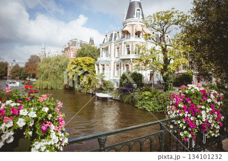 Flat design showing ornate canal house, wrought-iron railing, flower baskets and moored boat 134101232