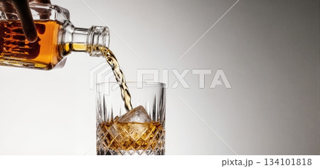Smooth whiskey pour into an ice-filled glass with a clean white background 134101818