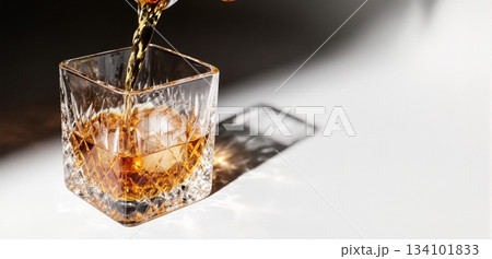 Smooth whiskey pour into an ice-filled glass with a clean white background Smooth whiskey pour into an ice-filled glass with a clean white background 134101833