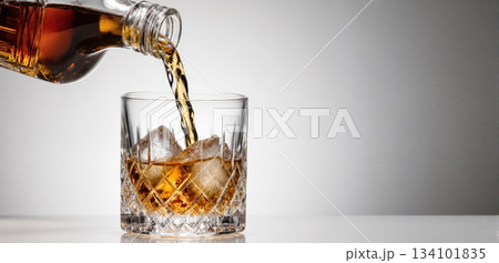 Smooth whiskey pour into an ice-filled glass with a clean white background Smooth whiskey pour into an ice-filled glass with a clean white background 134101835