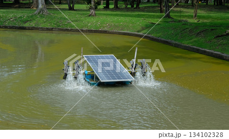 Solar-powered water turbine operating in the middle of a pond, showcasing clean energy technology 134102328